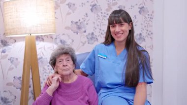 Nazik bakıcı, yaşlı bir kadının yanında oturuyor. Huzur ve destek sağlıyor.