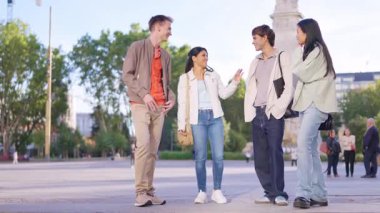 Çok ırklı genç arkadaşlar şehrin dışında bir arada durur, konuşur ve gülümserler.