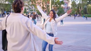 Bir kadın, bir şehir caddesinde arkadaşlarıyla buluşup kucaklaşmak için mutlu bir şekilde koşuyor.