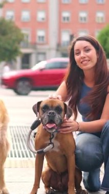 İki genç kadın boksör ve golden retriever köpekleriyle dışarıda eğleniyor.