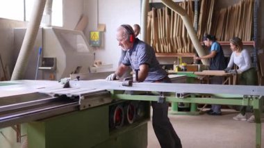 Bir marangozhanede tahta testereyle tahta kesen usta bir marangoz.