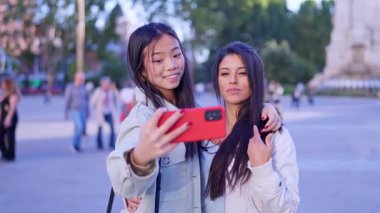 Mutlu lezbiyen çift akıllı telefonuyla selfie çekiyor ve parkta sevgiyle sarılıyorlar.