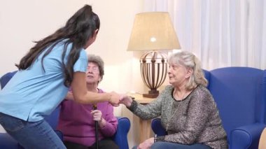 Genç bir kadın huzurevinde gülümseyen yaşlı büyükannesine şefkatle sarılıp öpüyor.