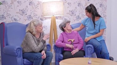 Yaşlı büyükannesiyle bakım evinde gülen genç bir kadın.