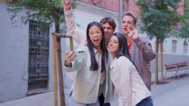 Mutlu çok ırklı arkadaş grubu akıllı telefonuyla selfie çekiyor ve birlikte komik suratlar yapıyorlar.