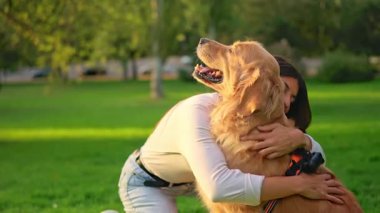 Mutlu genç bir kadın güneşli bir günde güzel köpeğini kucaklıyor.