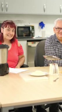 Fiziksel engelli insanlar yemek atölyesi sırasında birlikte gülümseyip öğreniyorlar.