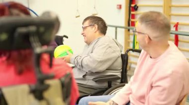 Tekerlekli sandalyedeki mutlu insanlar rehabilitasyon merkezinde eğlenceli bir grup aktivitesi yapıyorlar.