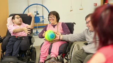 Tekerlekli sandalyedeki mutlu insanlar rehabilitasyon merkezinde eğlenceli bir grup aktivitesi yapıyorlar.