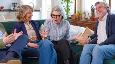 Bir grup animasyon kıdemli arkadaş bir kanepede oturur, konuşur ve gülümserler.