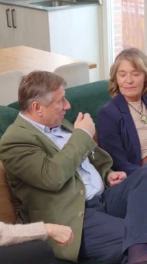 Oturma odasındaki kanepede oturan yaşlı insanlar, neşeli ve dostça bir sohbete girişmişler.