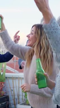 Bir grup mutlu kıdemli arkadaş terasta parti sırasında dans edip bira içiyorlar.