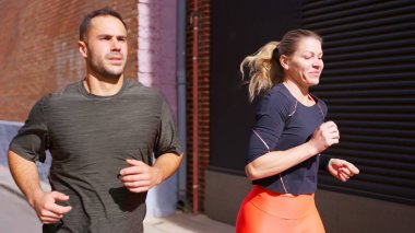 Erkek ve kadın birlikte dışarı koşuyorlar, sağlık ve egzersiz hedeflerine odaklanıyorlar.