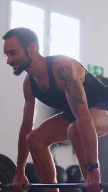 Ağır çekimde ağırlık kaldırma egzersizi sırasında ağır halter kaldıran dövmeli güçlü bir adam.