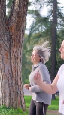 Bir grup aktif son sınıf öğrencisi parkta birlikte koşuyor ve ağır çekimde sağlıklı kalıyorlar.