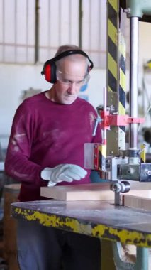 Prezervatif takan olgun bir zanaatkar atölyedeki tahta bloğu makinelerle kesiyor.