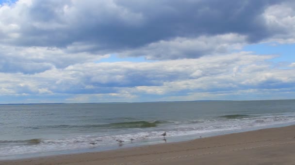 Nubes sobre olas tocando la playa de arena — Vídeo de stock