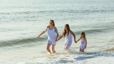 Aile akşam sahilde günbatımı sırasında yürüyüş.