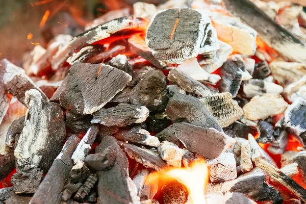 Carbón vegetal ardiente con llama de color naranja y foco selectivo brillante, en partes de las piezas alrededor de la — Foto de Stock
