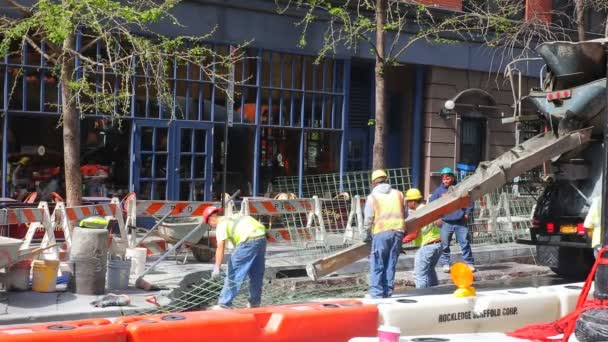 New York City - 20 April 2016: Bouw werknemers vast-cement in 42st - non-stop verbetering gebeurt in elke borough van New York City. Een Caterpilllar ligt in de achtergrond van de werknemers. — Stockvideo