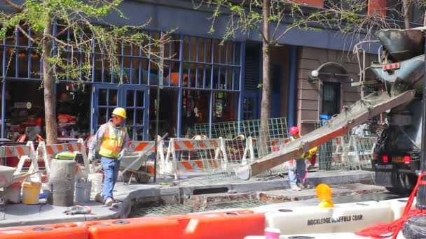 NUEVA YORK CITY - 20 DE ABRIL DE 2016: Trabajadores de la construcción colocan cemento en la calle 42 - la mejora continua ocurre en todos los barrios de la ciudad de Nueva York. Un Caterpilllar se encuentra en el fondo de los trabajadores . — Vídeos de Stock