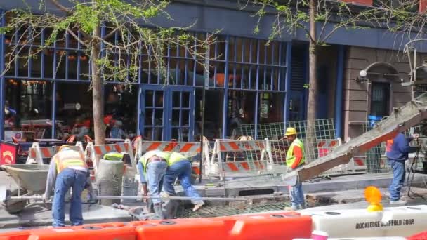 NUEVA YORK CITY - 20 DE ABRIL DE 2016: Trabajadores de la construcción colocan cemento en la calle 42 - la mejora continua ocurre en todos los barrios de la ciudad de Nueva York. Un Caterpilllar se encuentra en el fondo de los trabajadores . — Vídeos de Stock