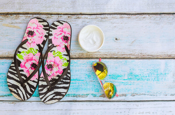 Beach accessories. Summer shoes and towel with sunglasses wooden background