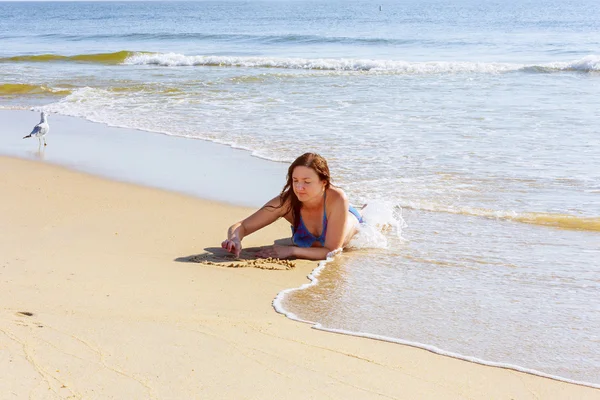 Mulher bonita escrevendo a palavra AMOR na areia — Fotografia de Stock