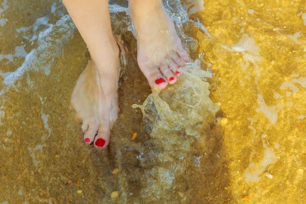 Jambes féminines galbées dans le sable près de l'océan — Photo