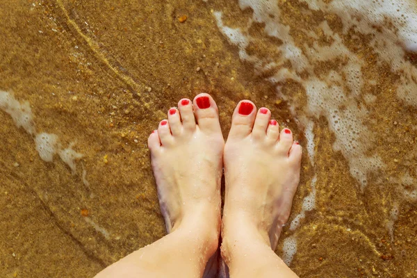 Formschöne weibliche Beine im Sand am Meer — Stockfoto