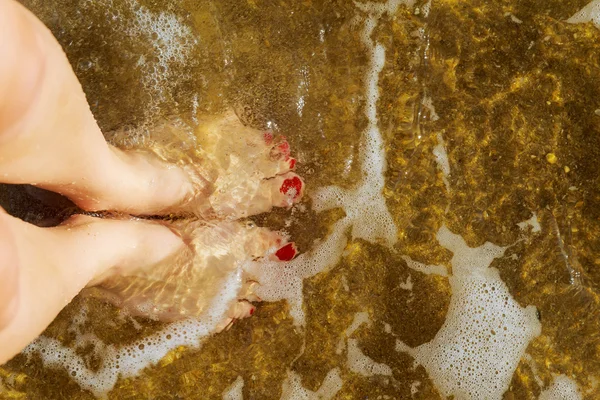 Formschöne weibliche Beine im Sand am Meer — Stockfoto