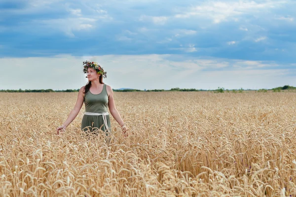 Красивая девушка на пшеничном поле с венком на голове — стоковое фото