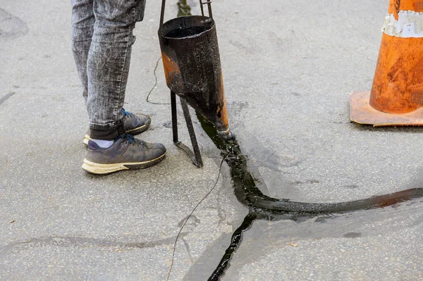 Man sealing asphalt driveway with filled cracks sealcoating selective focus