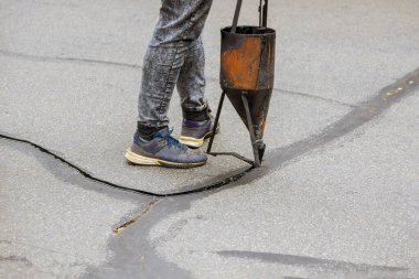 İşçilerin restorasyon çalışmaları çatlakları kapatarak asfalta sıvı mühür takarak yol üzerindeki yol koruyucu bir paltoyu asfaltlıyor.