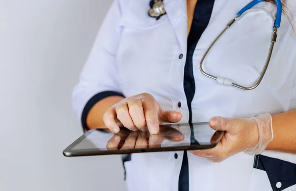 Female physician using digital tablet while standing near desk at clinic emergency hospital doctor at work.