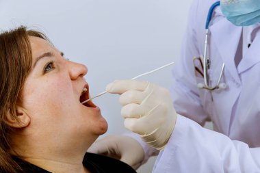 Covid-19 için PLR test koronavirüsü için ağız temizliği yapacak bir kadın doktor.