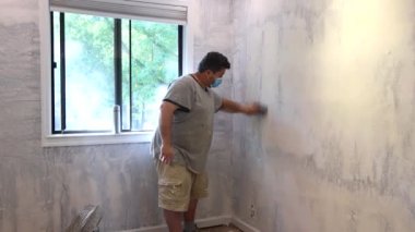 Müteahhit alçıpanı zımparalamak için kum malası kullanıyor.