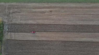 Tarlada tarla süren kırmızı traktörlü küçük ölçekli tarım.