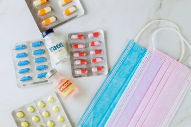Coronavirus vacine şişesi SARS-COV-2 COVID-19 'daki çeşitli ilaç hapları, haplar ve kapsüller koruyucu maske üzerindeki koronavirüs salgınıyla savaşmak için.