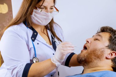 Klinik ortamdaki bir adam, bir sağlık görevlisi tarafından Coronavirus COVID-19 kapıp kapmadığını belirlemek için temizleniyor..