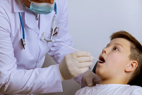Pracownik medyczny sprawdzi u nastolatka wymaz z jamy ustnej na obecność koronawirusu testowego PLR na obecność Covid-19 — Zdjęcie stockowe