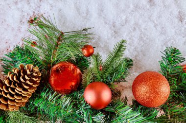 Çam kozalaklı fidan dalı, kar taneleri ve yılbaşı kar süslemeleri arka planında top