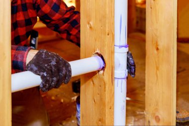 Plastik kanalizasyon borusundaki bir tesisatçı PVC borusuna tutkal yapıştırıyor.