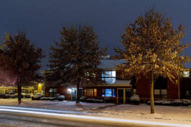 Konut alanı ve otopark akşamı karlı yolda yanan evler.