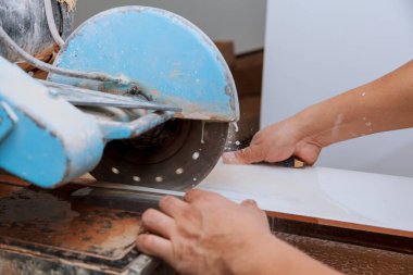 İşçi, binanın döşemesine döşeme döşemesi döşemesi döşenmesi için testere testeresi ile fayans kesti.