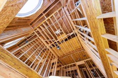 İnşaat kirişleri altında ahşap çerçeveli bir ev evin çatısını döşemiş.