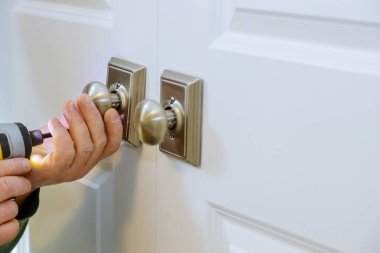 Çilingir işçisi eve yeni bir sahte kilit takıyor.