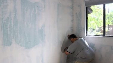 Sıvacı duvarları zımpara kağıdından bir işçinin eliyle düzeltiyor..