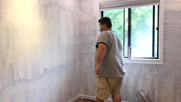 Seorang pria mengenakan debu pelindung topeng dan dinding sanding dengan balok sanding pada persiapan sebelum melukis. — Stok Video
