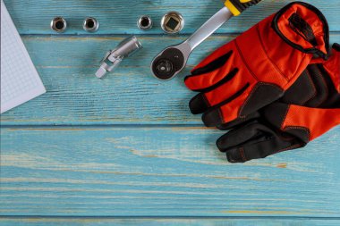 Profesyonel otomotiv seti üzerindeki koruyucu eldivenler ahşap arka planda anahtar krom araçlar.